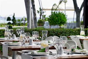 Gartentisch des Atlantica Miramare Beach Hotels, gedeckt mit Geschirr und Gläsern.