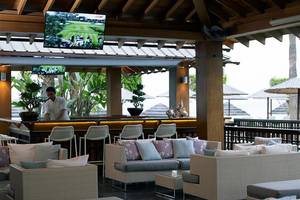 Innenansicht der Bar im Atlantica Miramare Beach Hotel mit Barkeeper und Sofas.