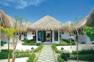 Außenbereich des Cinnamon Dhonveli Maldives mit mehreren weißen Bungalows und begrünten Gärten.