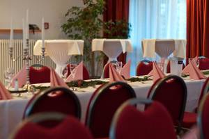 Bankettsaal im Leonardo Hotel Hamburg Elbbrücken mit festlich gedeckten Tischen.