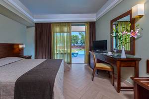Hotelzimmer im Porto Platanias Beach Resort & Spa mit Bett, Schreibtisch und Aussicht auf den Pool.