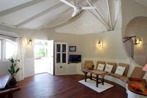 Wohnbereich des Nika Island Resort & Spa mit weißem Interieur, Holzboden und Couchsofa.