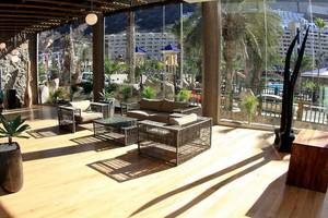 Hotellounge des LIVVO Costa Taurito mit Möbeln und Pflanzen, Blick auf Gebäude und Palmen.