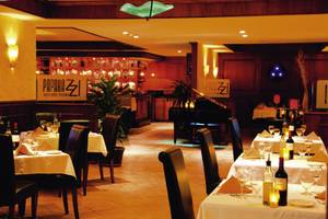 Innenbereich des Paparazzi Restaurants mit Tisch, Stühlen, Weinflaschen und Dekoration.