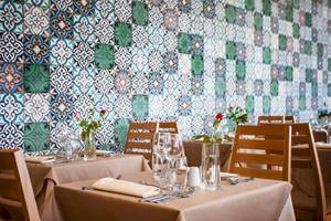 Restaurant-Innenbereich des Bianca Beach Resorts mit blau-grüner Wandfliesen und gedeckten Tischen.