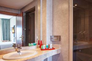 Badezimmer im Bianca Beach Resort mit Spiegel, Waschbecken und Duschbereich.