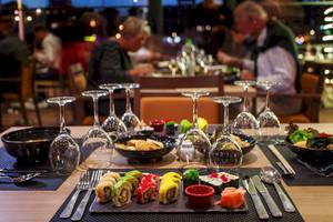 Restauranttisch im Bianca Beach Resort mit Sushi, Getränkegläsern und Geschirr.