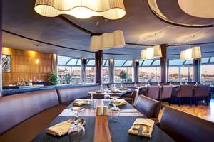Innenansicht des Restaurants im Bianca Beach Resort mit Tisch, Gläsern und Blick auf die Stadt.