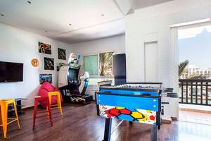 Spielzimmer im Bianca Beach Resort mit Fernseher, Spielkonsole, Tischfußball und bunten Stühlen.