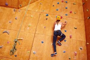 Eine Frau klettert an einer Wand im Indoor-Climbing-Center.
