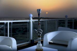 Sonnenuntergang auf dem Balkon des Wyndham Garden Salalah Mirbat mit einer Shisha auf einem Tisch.