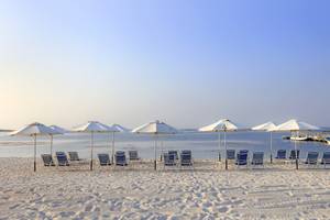 Strand des Wyndham Garden Salalah Mirbat mit Liegen und Umbrellas am Meer