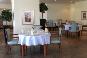 Wyndham Garden Salalah Mirbat Speisesaal mit Tisch und Stühlen, Pflanzen und Gemälden an den Wänden