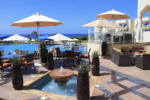 Pool-Terrasse im Wyndham Garden Salalah Mirbat mit Tischen, Stühlen und Sonnenschirmen