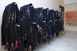 Mehrere schwarze Aqua Lung Tauchanzüge sind an einer Wand im Wyndham Garden Salalah Mirbat Hotel aufgehängt.