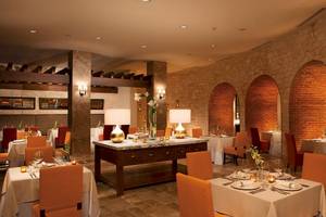 Innenbereich des Restaurants im Secrets Akumal Riviera Maya mit runden Bögen und Steinwänden.