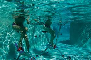 Zwei Personen schwimmen mit Schwimmtrainer im Pool des Secrets Akumal Riviera Maya
