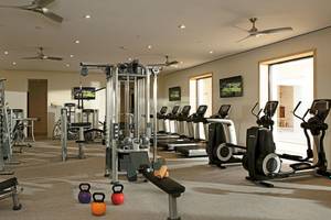 Fitnessstudio im Hotel Secrets Akumal Riviera Maya mit verschiedenen Trainingsgeräten und Fernsehern.