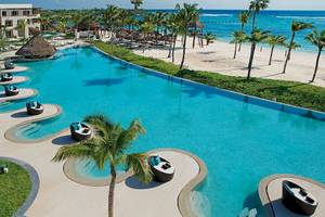 Luftaufnahme des Infinity-Pools im Secrets Akumal Riviera Maya Hotel mit Loungesesseln und Blick auf den Strand
