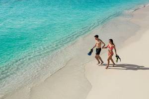 Ein Paar mit Schnorchelausrüstung läuft am Strand des Secrets Akumal Riviera Maya.