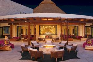 Hotellounge bei Nacht des Secrets Akumal Riviera Maya mit einem zentralen Feuerplatz und umliegenden Möbeln.