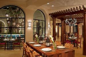 Innenansicht des Restaurants im Secrets Akumal Riviera Maya Hotel mit Holztischen, Stühlen und einer Pergola.