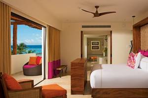 Zimmer im Secrets Akumal Riviera Maya Hotel mit Meerblick, Bett, Kissen, und Möbeln.