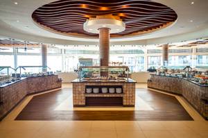 Buffetbereich im Reef Coco Beach Hotel mit vielen Gerichten und modernen Holzböden.