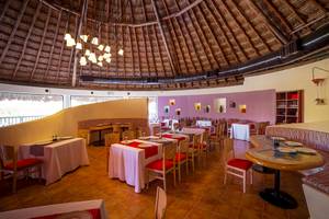 Speisesaal im Hotel The Reef Coco Beach mit runden Tischen und roten Stühlen.