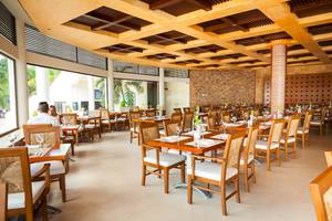 Innenansicht des Restaurants im Reef Coco Beach Hotel mit gedeckten Tischen und Stühlen.