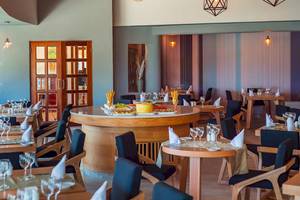 Innenansicht des Restaurants im Reef Coco Beach Hotel mit runden Tischen und Stühlen.