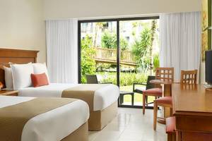 Zwei Betten in einem Hotelzimmer mit Blick auf eine Terrasse und einen Garten