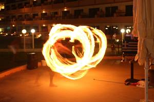 Eine Feuershow vor dem Kiani Beach Resort Hotel bei Nacht mit einem Performer und brennenden Seilen.