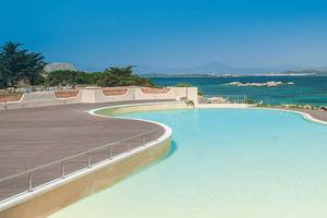 Außenpool des Cala Cuncheddi Hotels mit Blick auf das Meer und Berge.