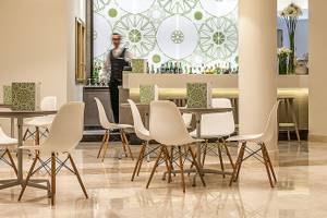 Cala Cuncheddi Hotellounge mit weißen Stühlen und runden grünen Wandmustern