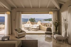 Wohnbereich im Cala Cuncheddi Hotel mit Blick auf das Meer und die Berge.