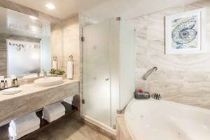Badezimmer im Ocean Blue & Sand by H10 mit Badewanne, Dusche und Waschbecken.