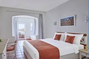 Innenansicht eines Hotelzimmers im JAZ Neo Reef Marsa Hotel mit einem Bett, Schreibtisch, Stühlen und Balkon