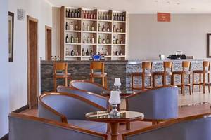 Barbereich im JAZ Neo Reef Marsa Hotel mit Barhockern und Getränken.
