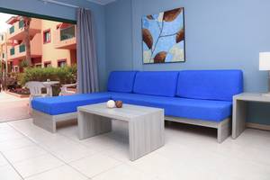 Wohnzimmer im Bluesea Aloe Corralejo Hotel mit blauem Sofa, Tisch und Lampe.