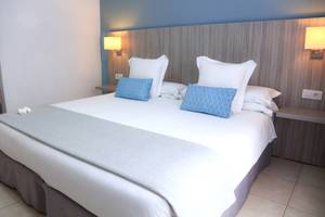Hotelzimmer im Bluesea Aloe Corralejo mit Bett, Kissen und Nachttischen.