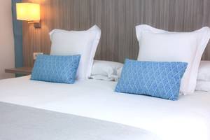 Ein Bett im Bluesea Aloe Corralejo Hotel mit weißen und blauen Kissen.