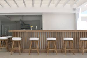 Ein modernes Hotelbar mit Holztheke und weißen Barhockern.