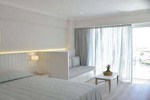 Ein Hotelzimmer im Sunrise Gardens mit weißem Bett, Leseecke und Aussichtsfenster.
