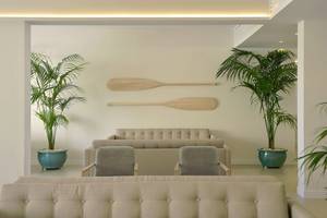 Wohnzimmer mit Sofas, Palmen und Rudern an der Wand im Sunrise Gardens Hotel.