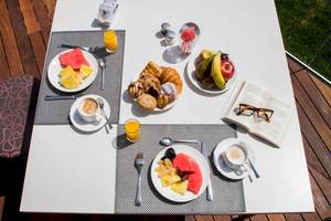 Frühstückstisch auf der Terrasse des Torre del Mar Hotels mit Früchten, Gebäck und Getränken.