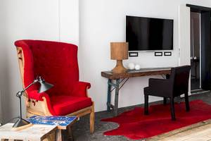 Inneneinrichtung des Myconian Avaton Resorts mit rotem Stuhl, Schreibtisch und Fernseher.