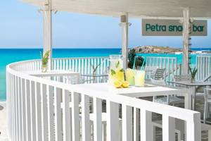 Außenterrasse des Nissi Beach Resorts mit Blick auf das Meer und einem Glas Limonade