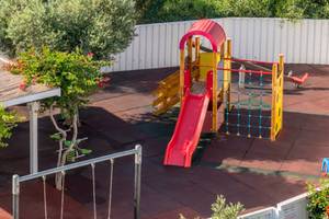 Kinderspielplatz im Nissi Beach Resort mit Rutsche, Schaukel und Klettergerüst.