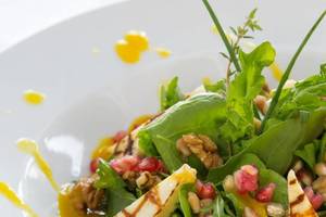 Ein Salat mit Rucola, Granatapfel, Walnüssen und Dressing.